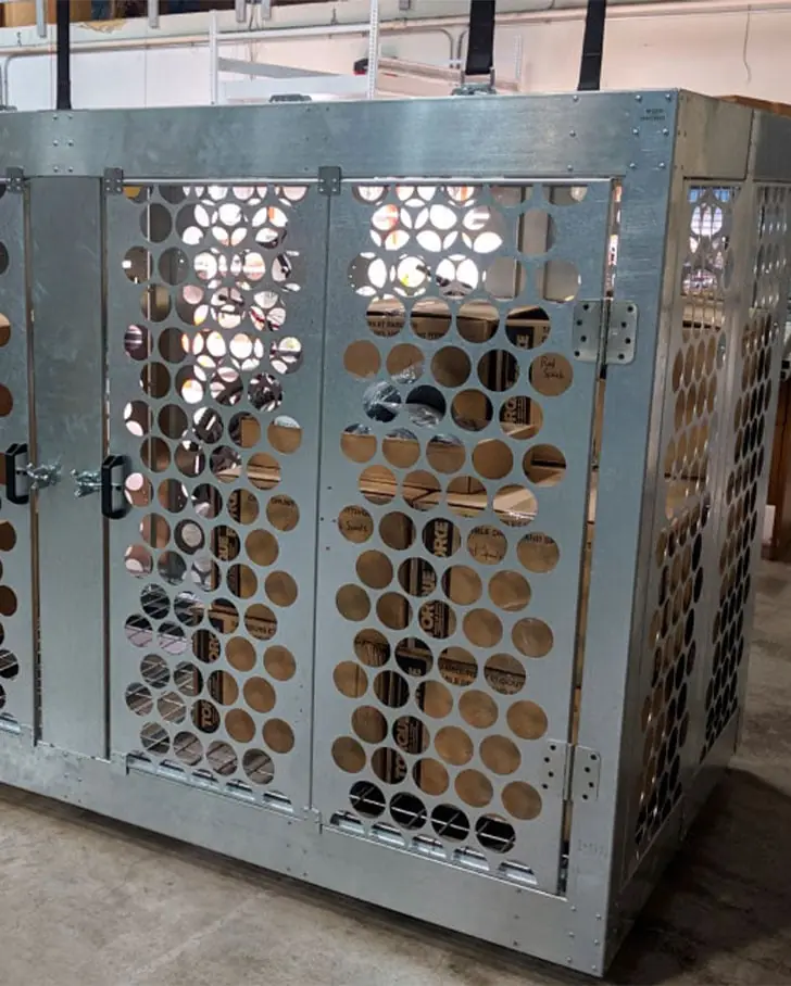 Galvanized perforated steel overhead storage cage with lockable double doors hanging from ceiling lift straps, used for high-density museum collection and back-of-house storage