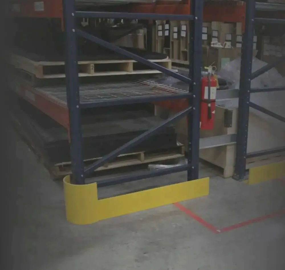 Yellow end-of-aisle guard anchored around the base of a pallet rack end frame