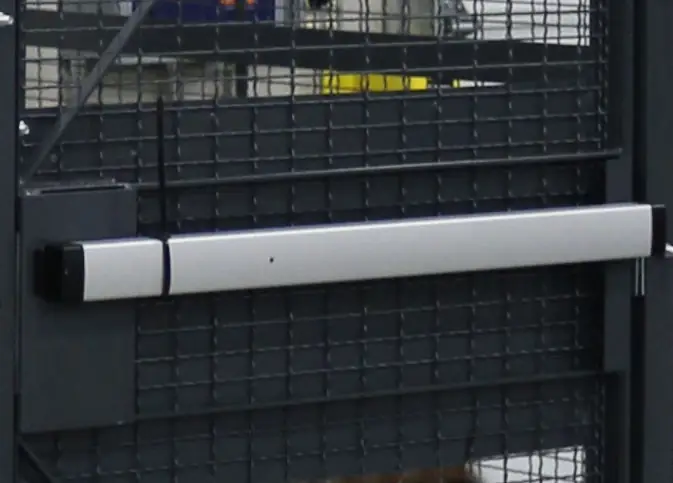 Push bar exit device on a black wire mesh cage door