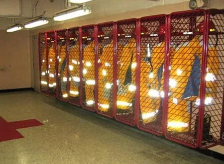 Red Rack turnout gear lockers lining a gear room wall under overhead lighting