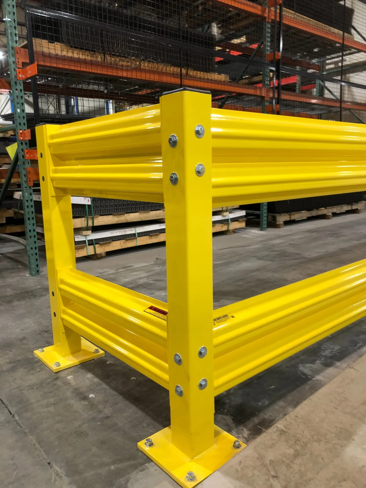 Yellow SpaceGuard AisleGuard industrial guardrail with double rails along a pallet rack aisle