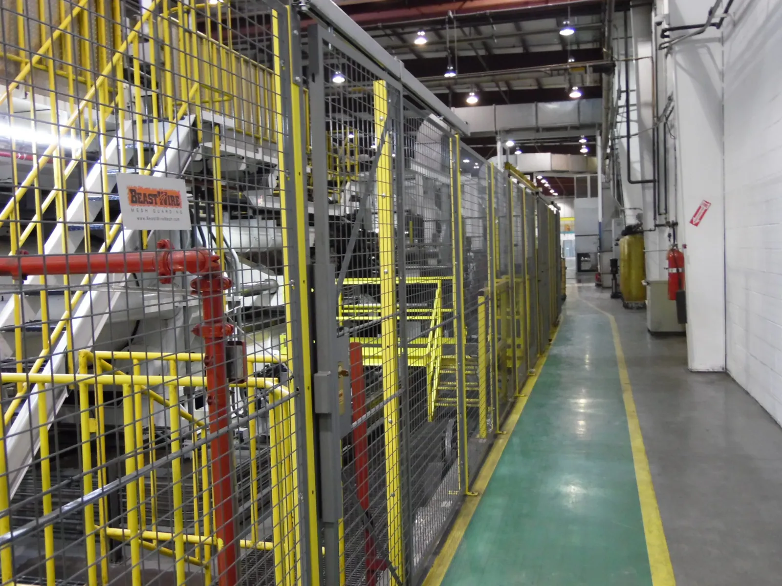Gray SpaceGuard BeastWire machine guarding separating an equipment area from a warehouse aisle