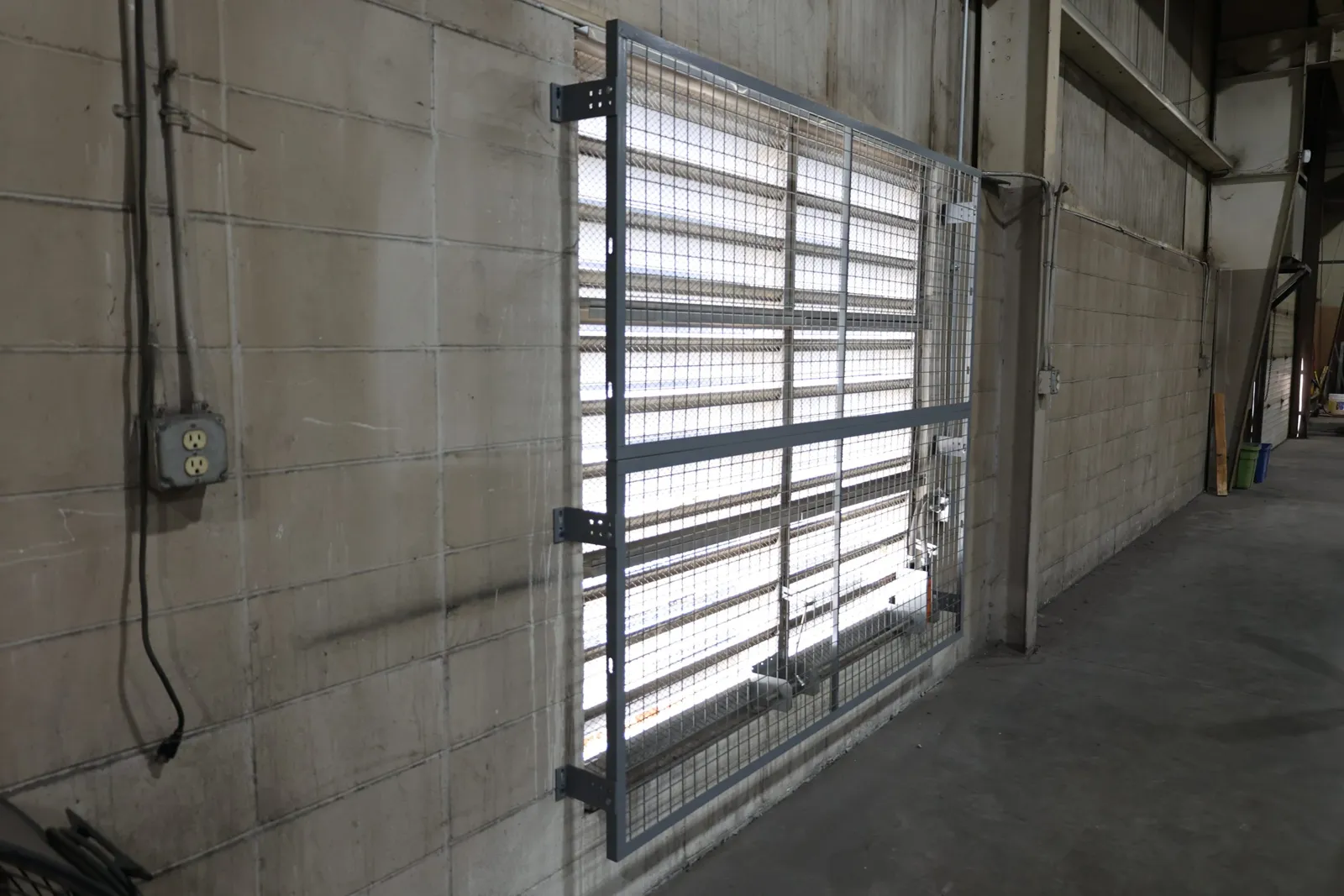Gray SpaceGuard BeastWire welded wire window guard mounted over a window on a block wall
