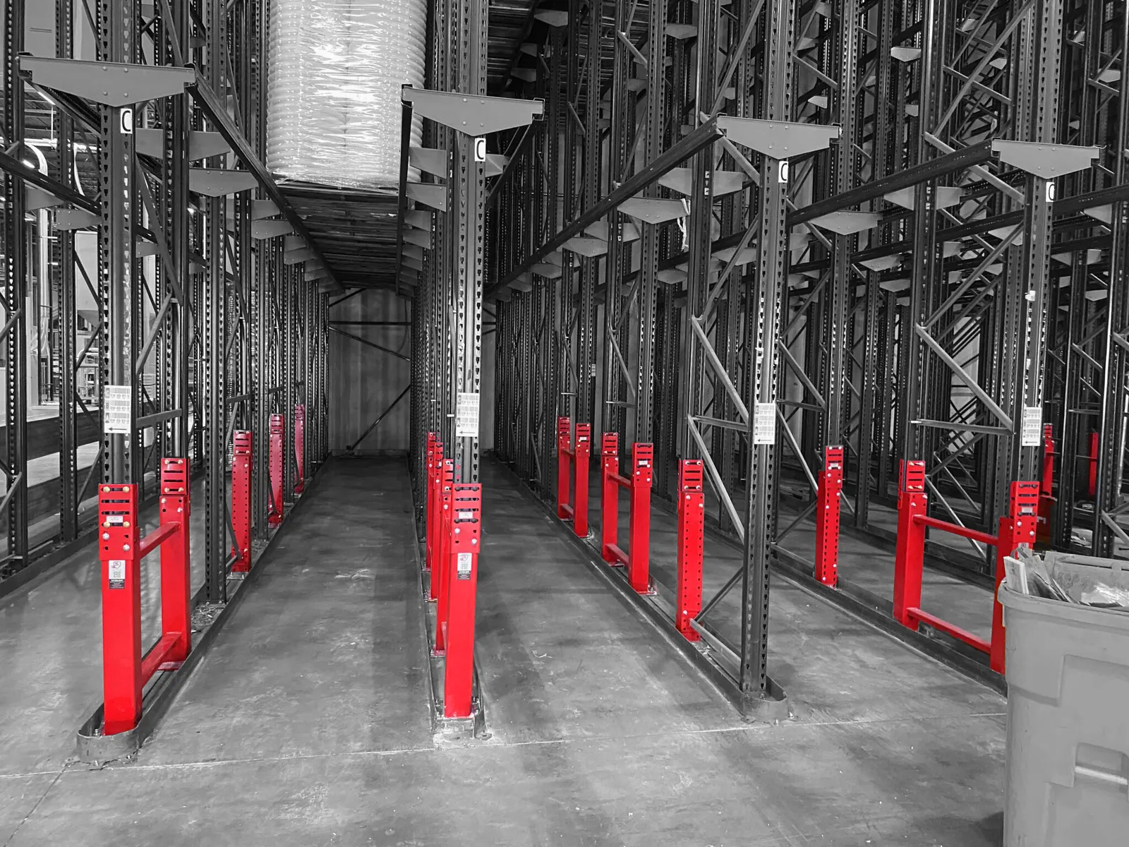 Red SpaceGuard Centurion Row Guards protecting upright pairs in a drive-in pallet rack