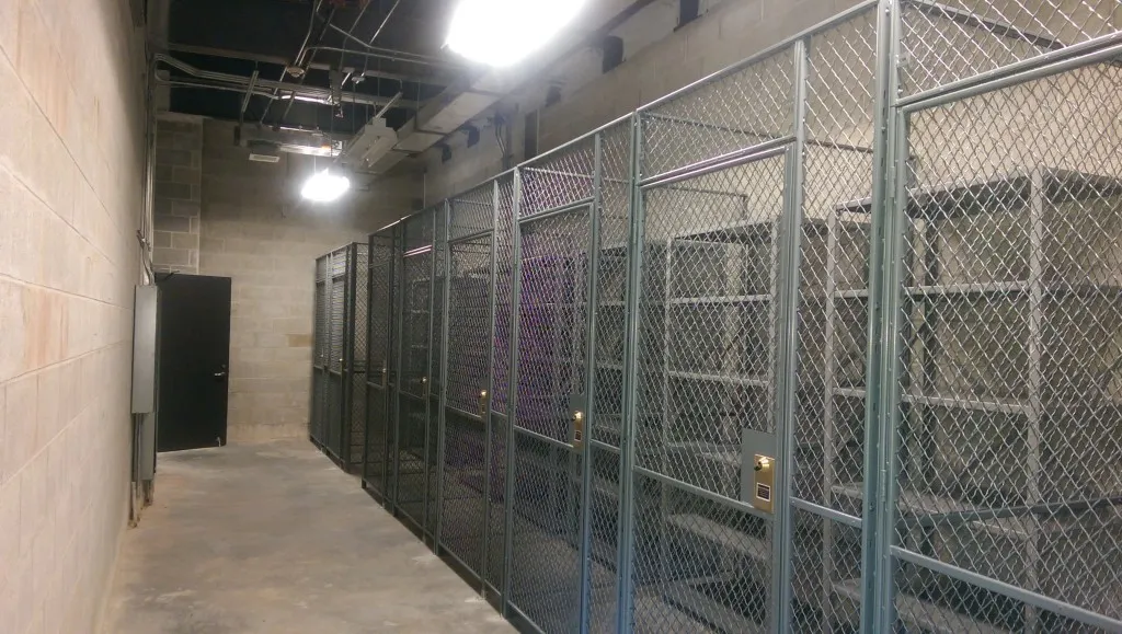 Row of gray SpaceGuard FordLogan woven wire storage lockers along a hallway