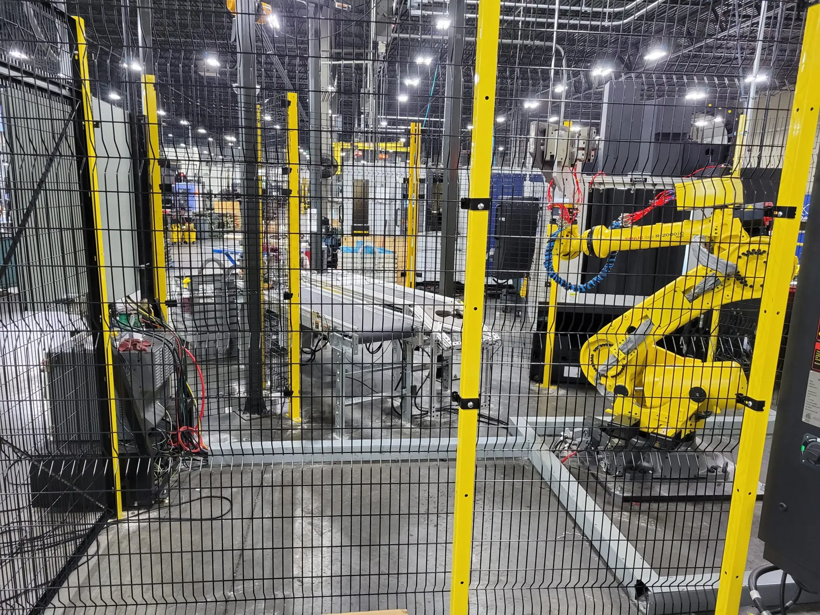 SpaceGuard RageWire robotic guarding with yellow posts and black mesh around a yellow industrial robot cell