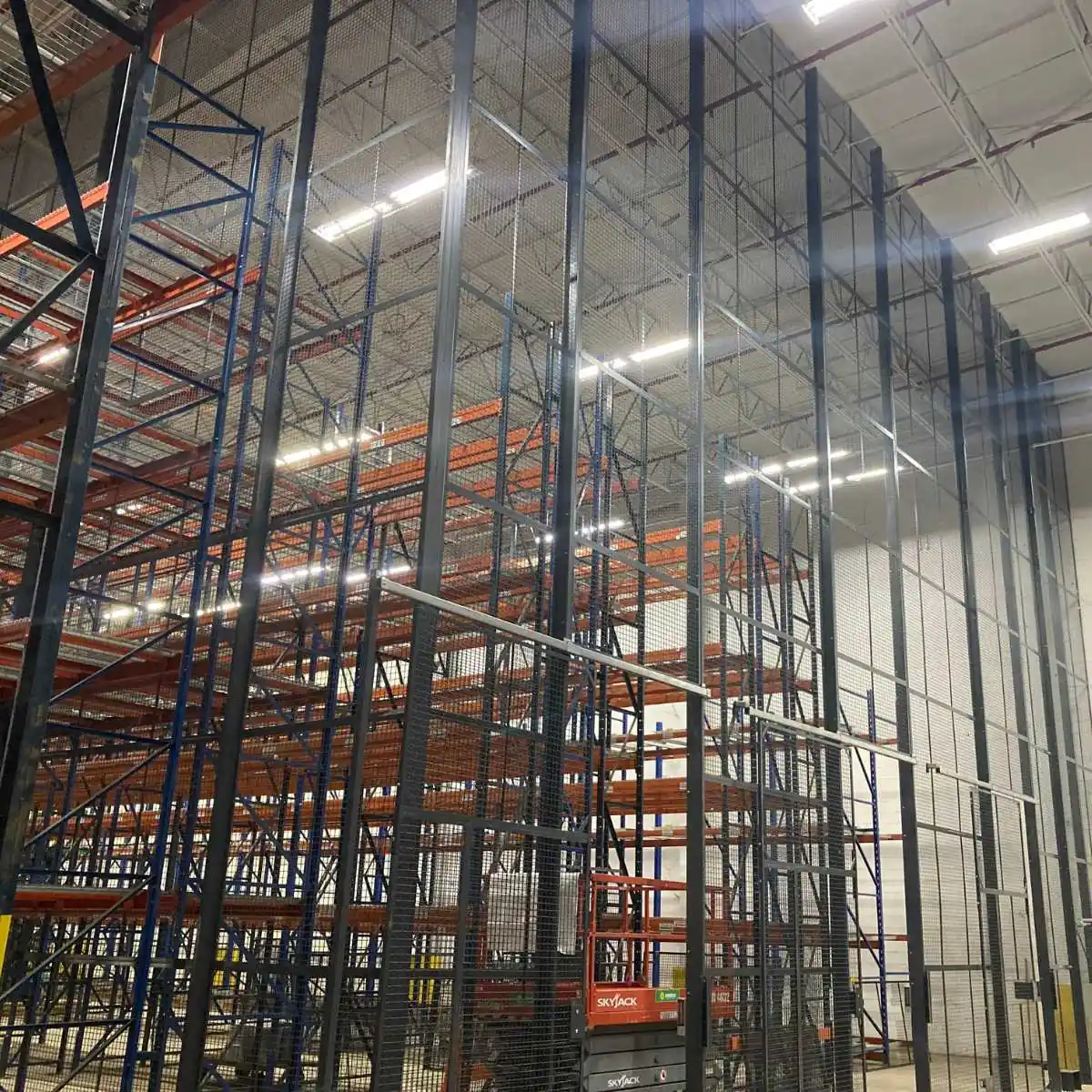 Tall black wire mesh aerosol storage enclosure built to the roof deck around pallet racking