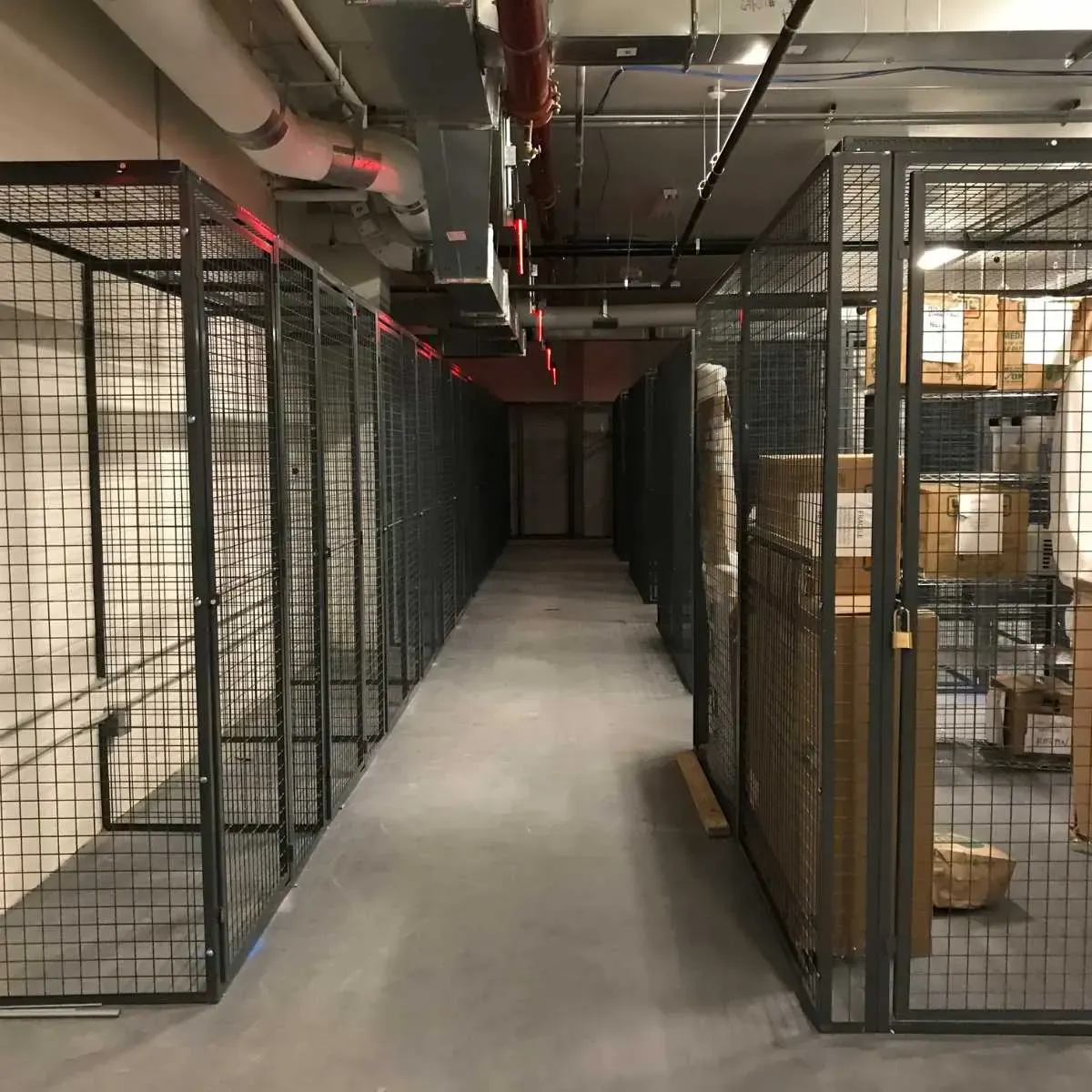 Long aisle between two rows of wire mesh tenant storage cages