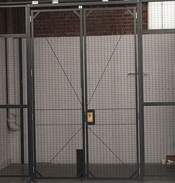 Double hinged wire mesh partition door with two leaves and center lock in a Wire Crafters cage