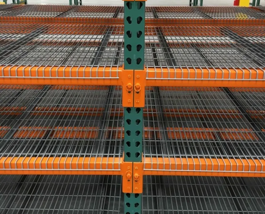 Close-up of wire decks with waterfall edges over orange step beams, beam connectors seated on a green teardrop upright with locking pins