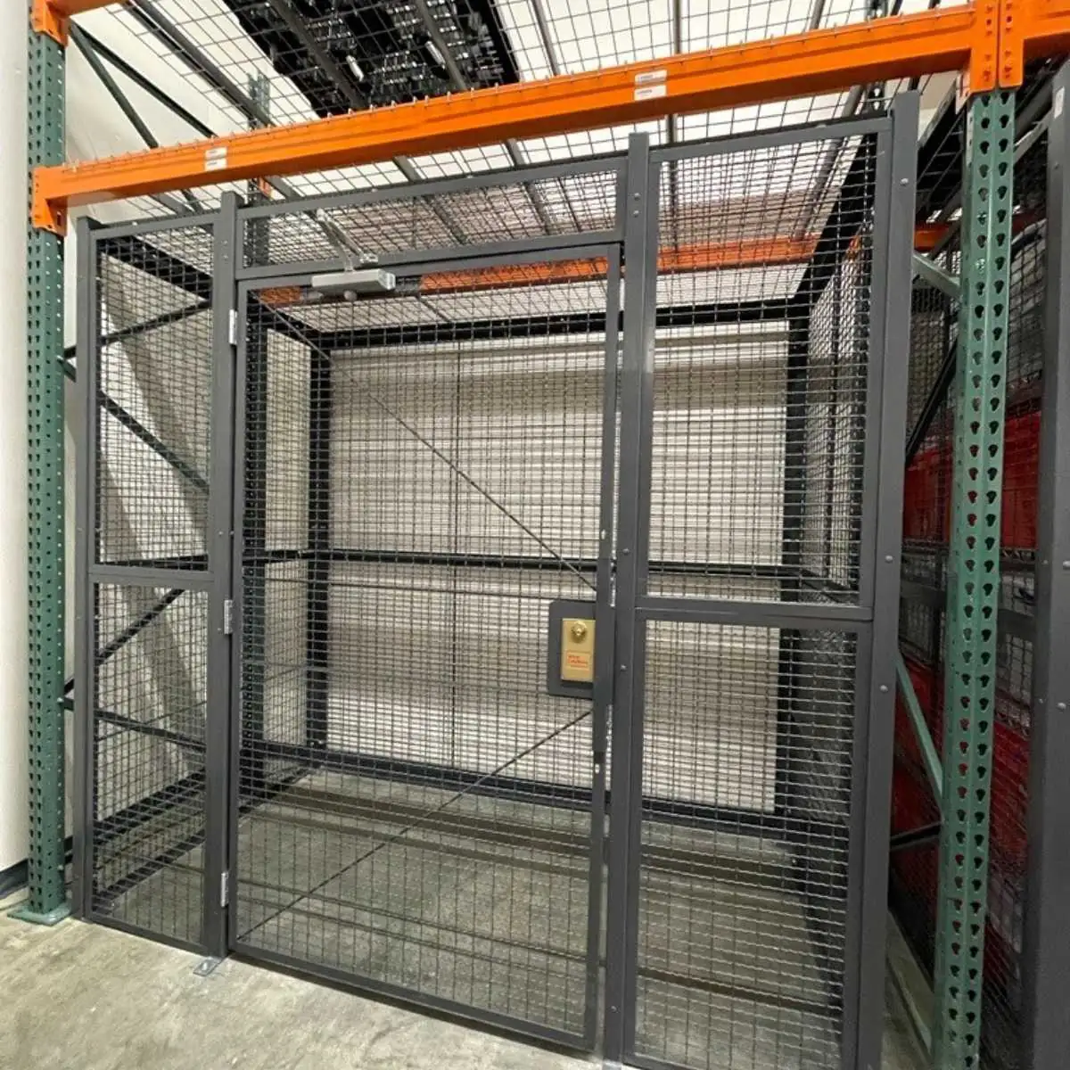 Wire mesh security cage with a hinged door and mesh top built into a pallet rack bay
