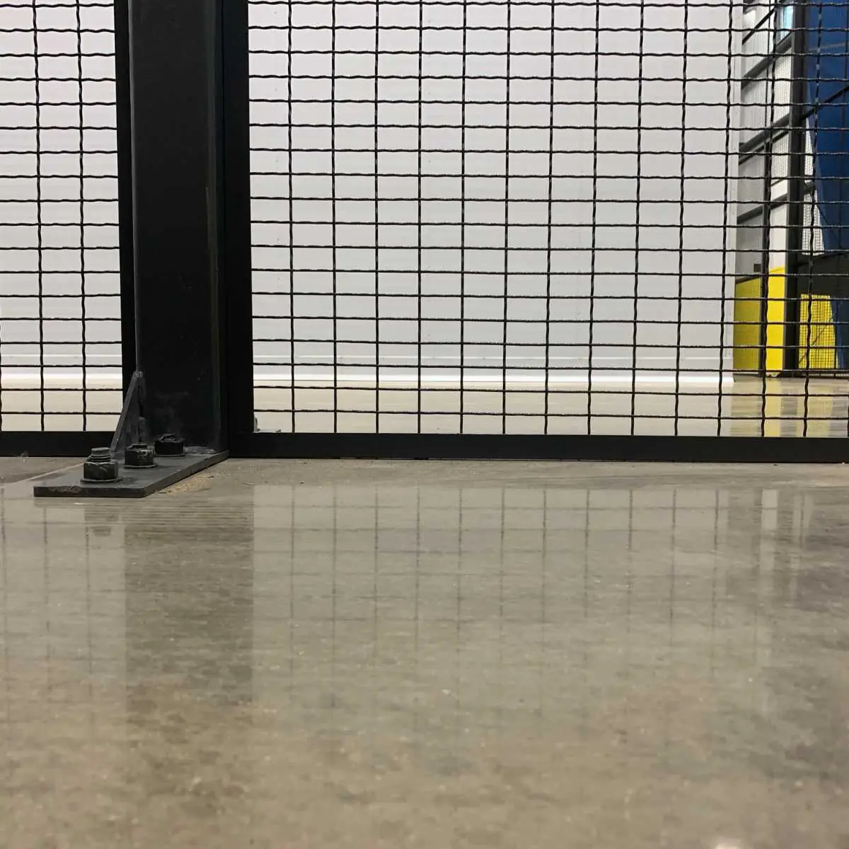 Long straight run of wire mesh partition panels anchored to a warehouse floor